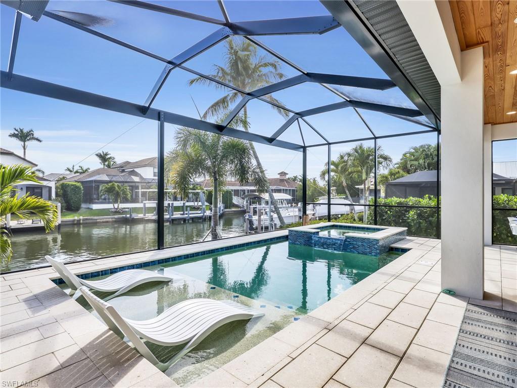Integrated pool / spa with glass enclosure, a sunroom, a water view, a patio, and a residential view