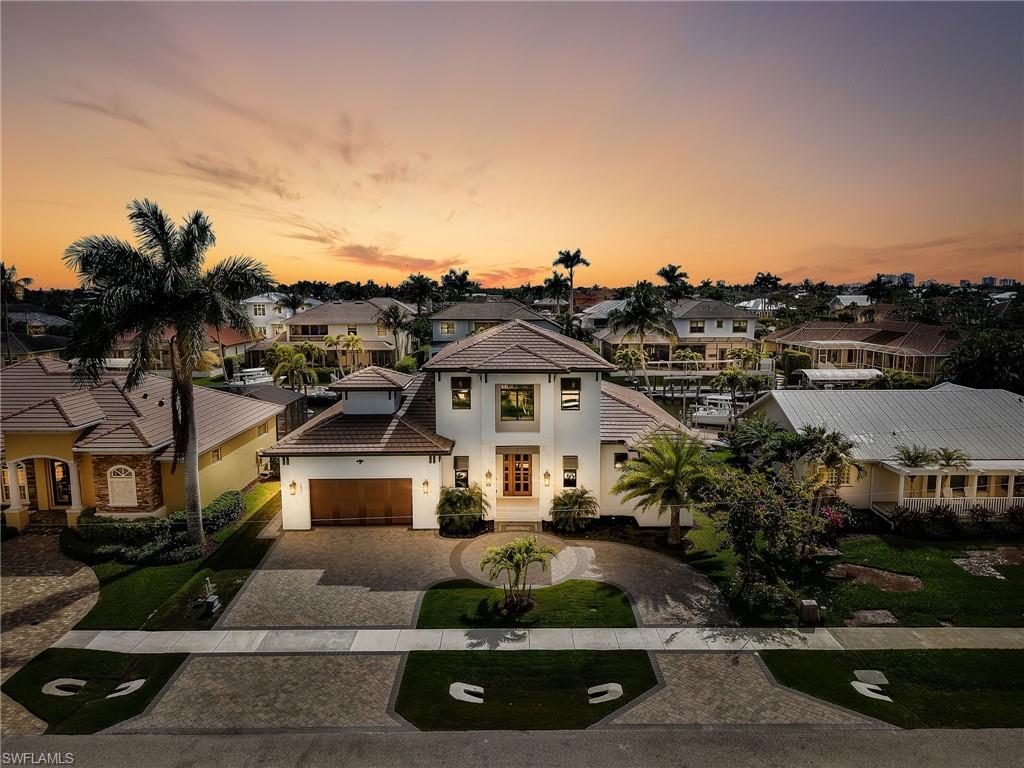View of front of property with decorative driveway, a residential view, stucco siding, and a tiled roof