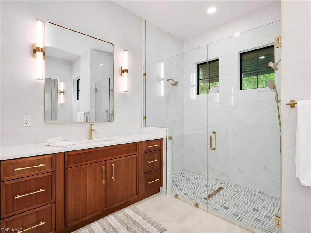 Full bathroom featuring vanity and a marble finish shower