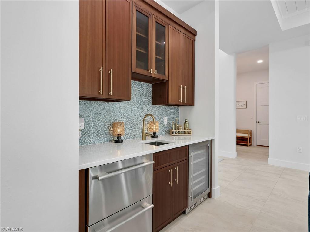 Kitchen with glass insert cabinets, stainless steel dishwasher, recessed lighting, light stone countertops, and wine cooler