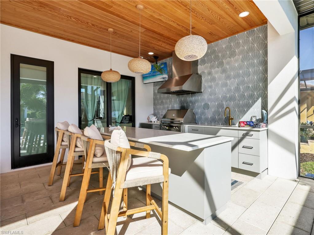 Kitchen with modern cabinets, pendant lighting, wood ceiling, decorative backsplash, and white cabinetry