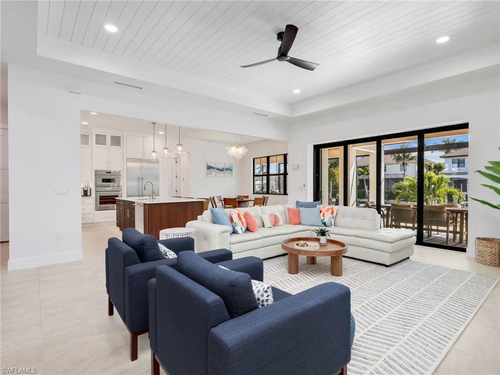Living room featuring a ceiling fan, a chandelier, and a wood tray ceiling
