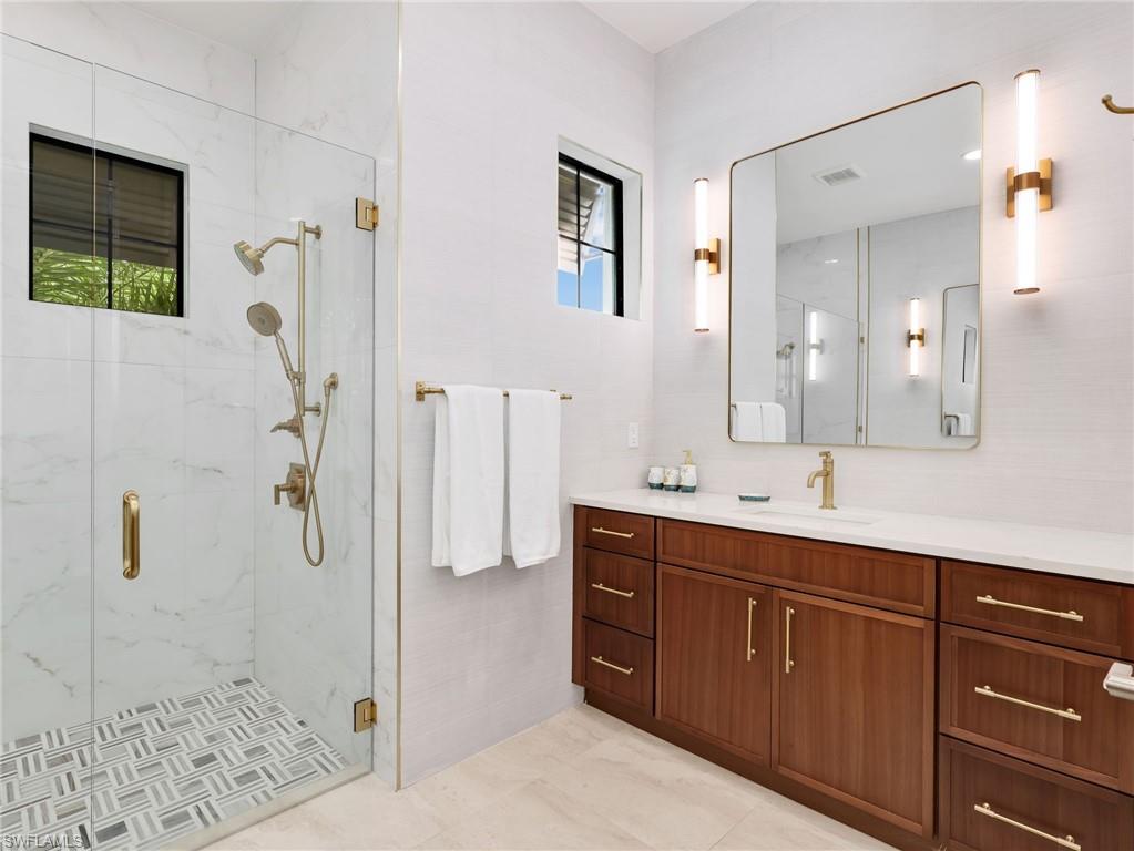 Full bath featuring vanity and a marble finish shower