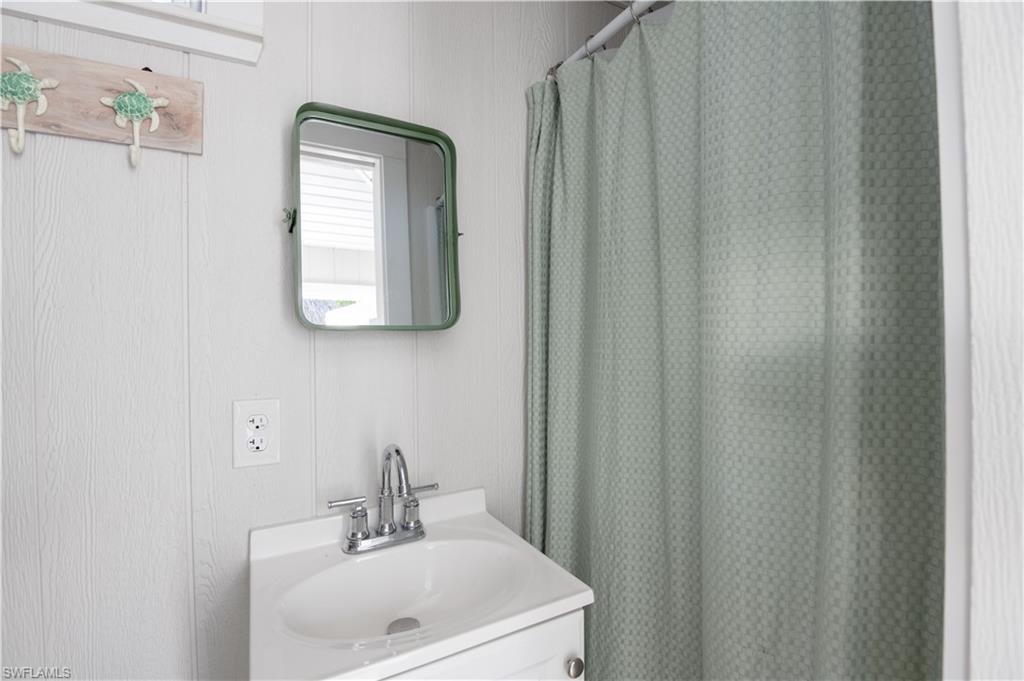 Full bath featuring curtained shower and vanity