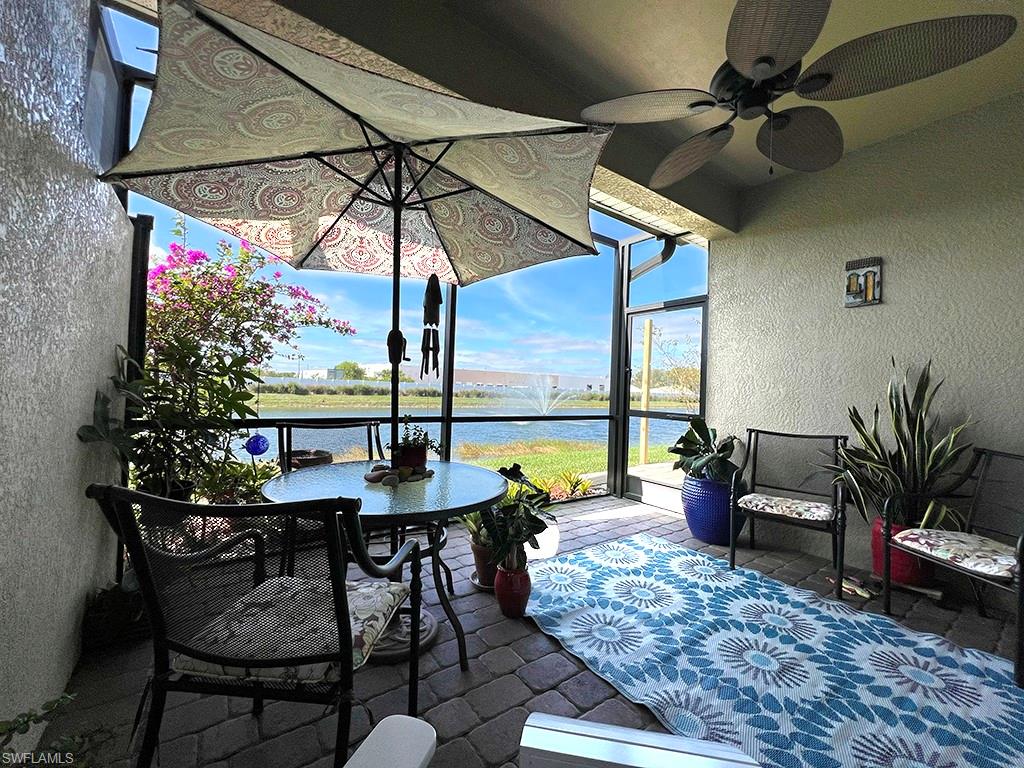 View of patio / terrace featuring a sunroom, glass enclosure, a water view, and a ceiling fan