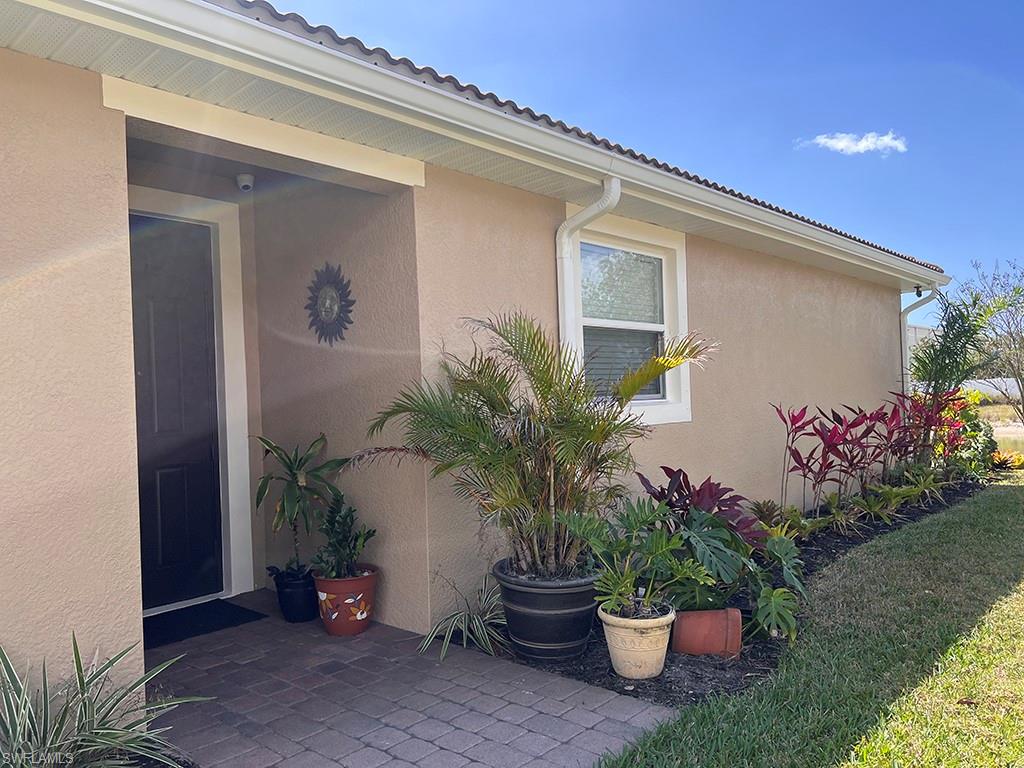 View of side of home with stucco siding, a patio, and a lawn