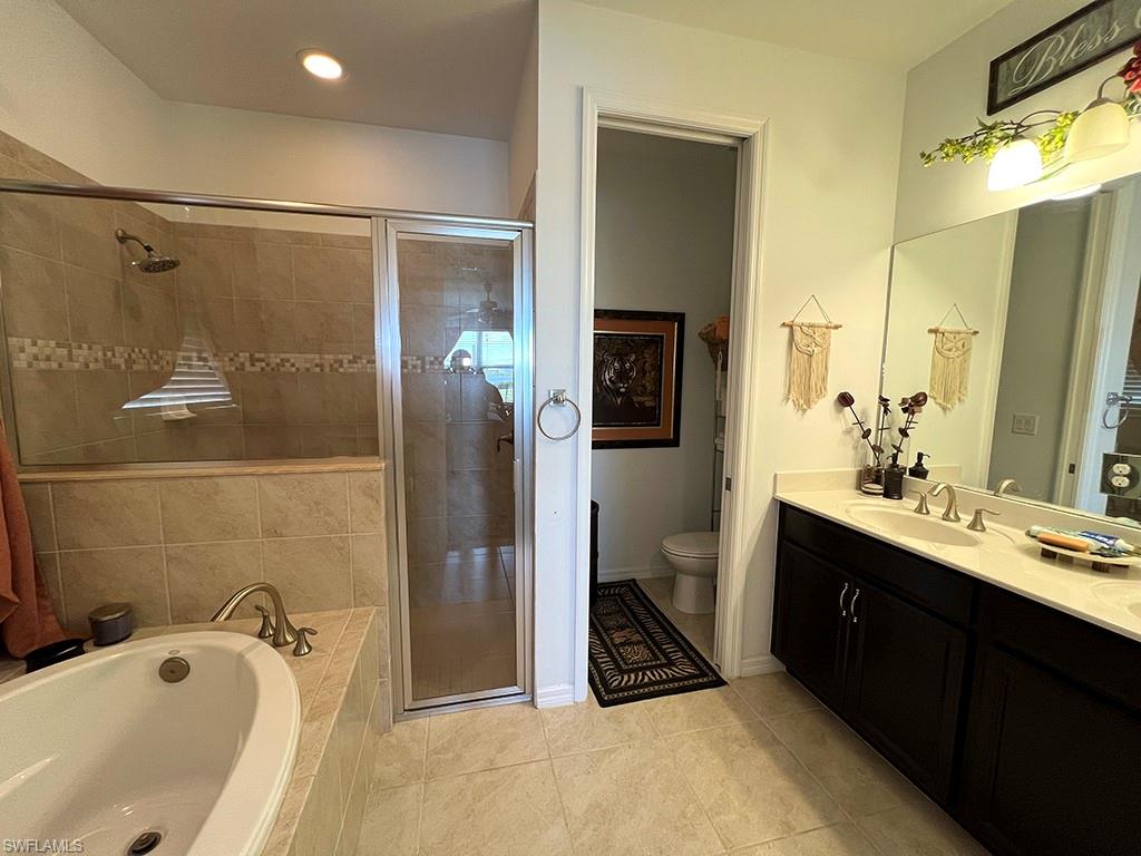 Bathroom featuring double vanity, a garden tub, a stall shower, and light tile patterned floors