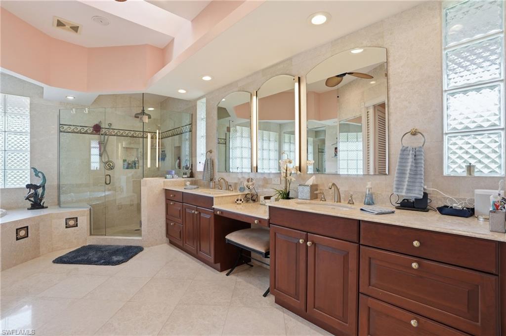 Bathroom featuring two vanities, a shower stall, a bath, light tile patterned floors, and ceiling fan