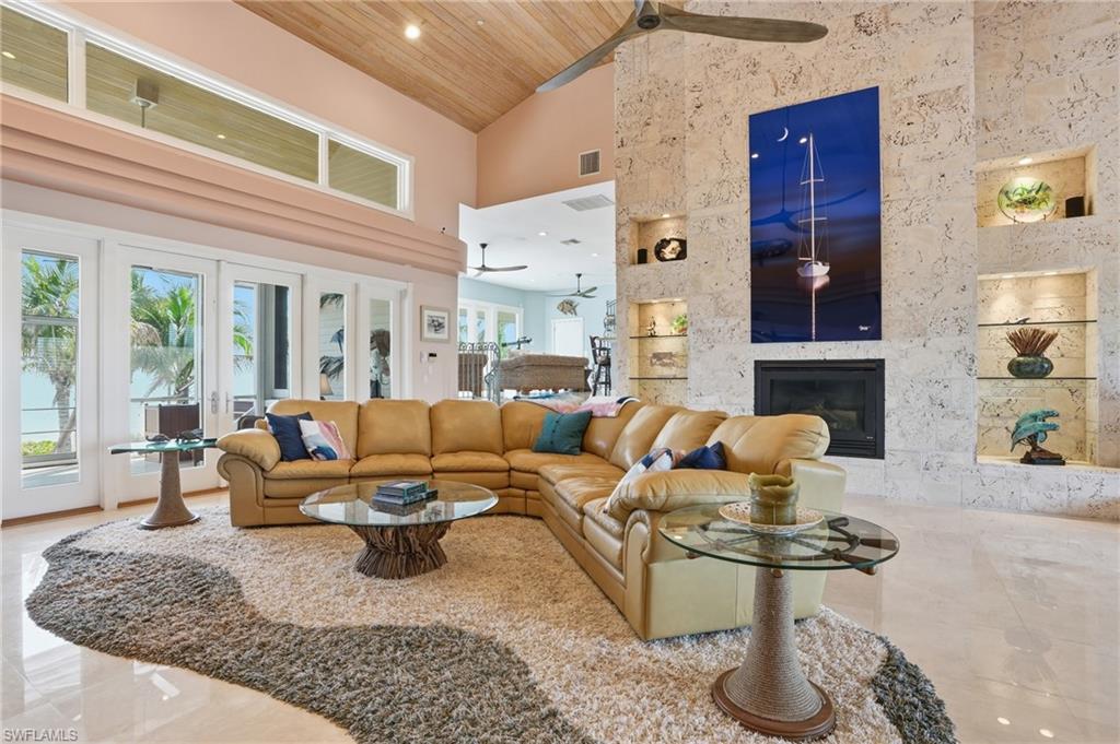 Living room with a vaulted wooden ceiling, a premium fireplace, recessed lighting, built in shelves, and a ceiling fan