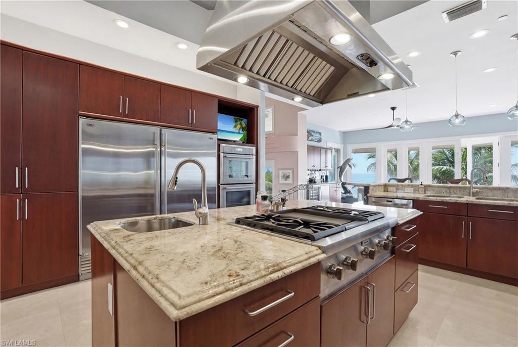 Chef’s kitchen with gas cooktop, prep sink, Thermador double ovens, Sub Zero refrigeration, custom cabinetry, and a statement stainless hood