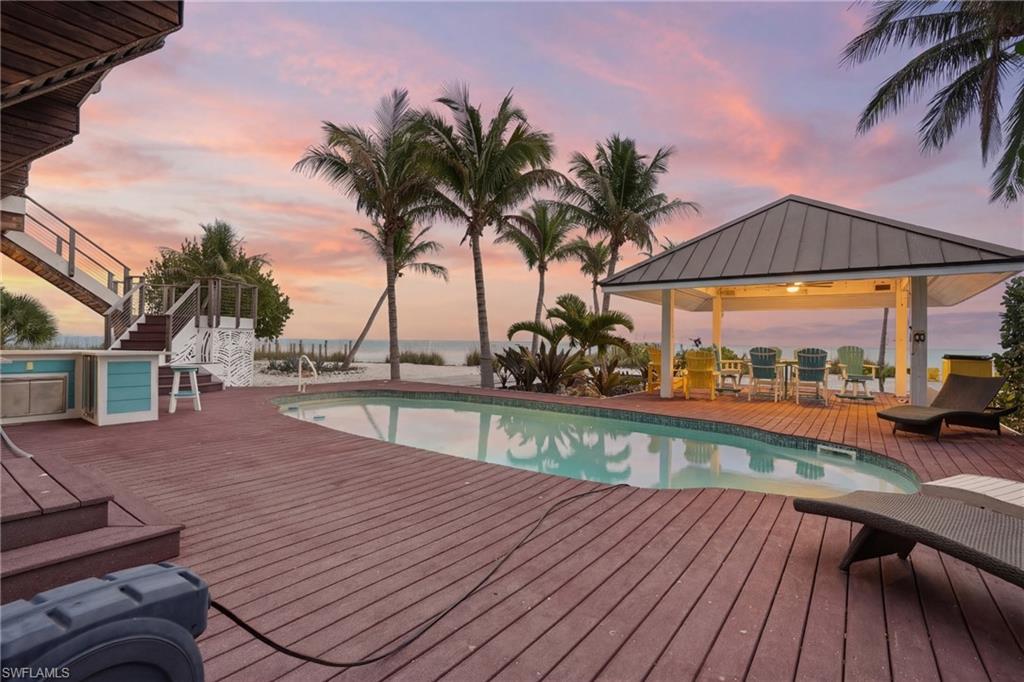 Pool at dusk with a deck, an outdoor pool, and a gazebo