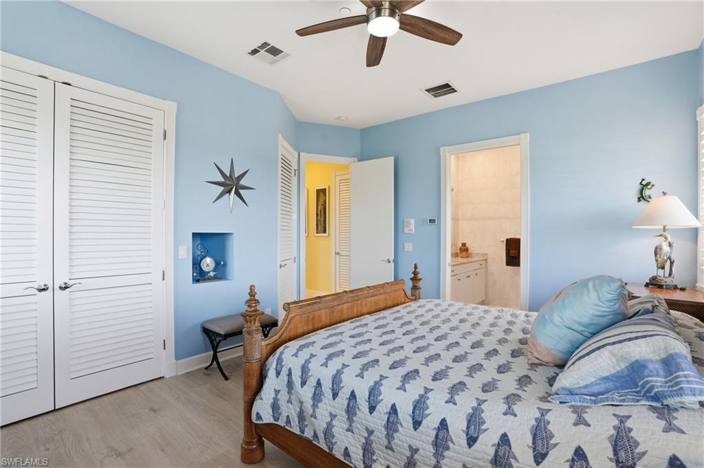 Bedroom with a closet, light wood-style flooring, a ceiling fan, and ensuite bathroom