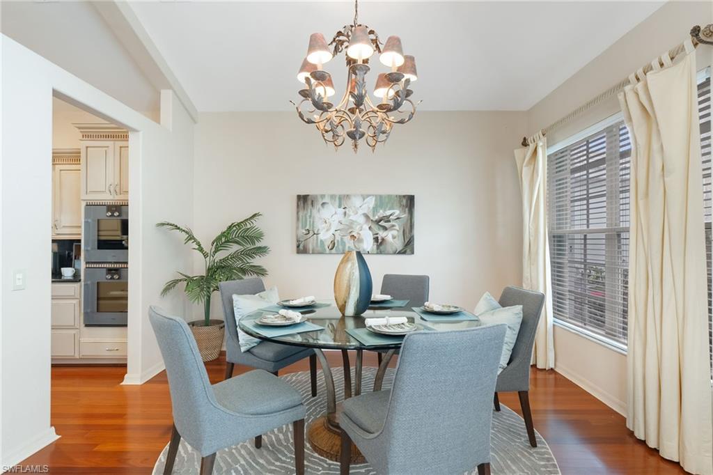 Formal dining space featuring wood-finish flooring, a decorative chandelier, and a large window with privacy blinds
