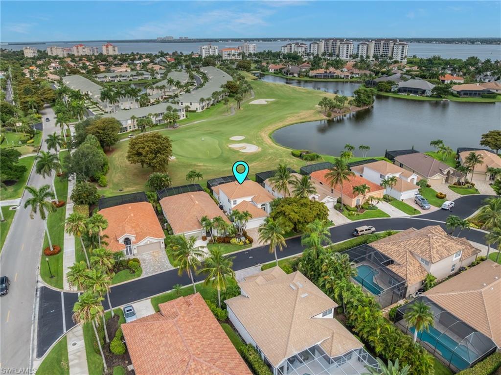 Aerial perspective showcasing residential properties bordering a golf course and a body of water
