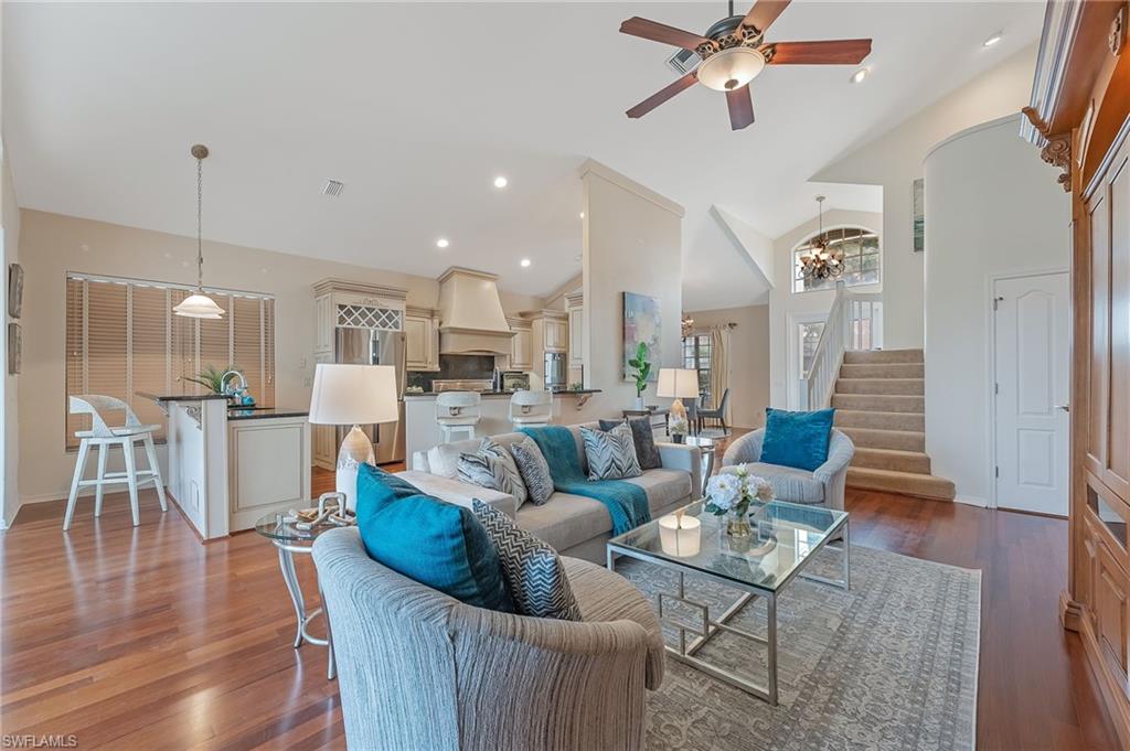 Open-concept living area featuring rich wood-finish flooring, vaulted ceilings, and a ceiling fan