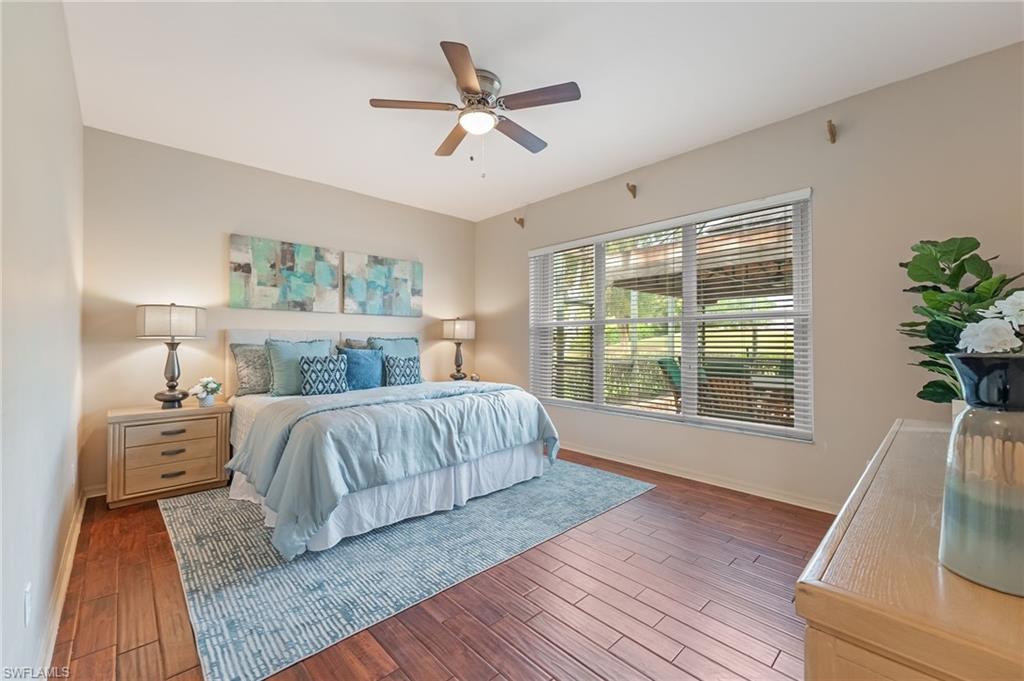 Bedroom featuring wood-finish flooring, a ceiling fan with integrated lighting, a large window with horizontal blinds, and neutral wall tones