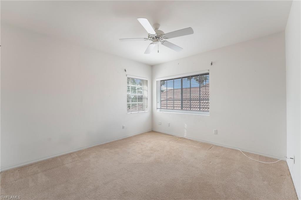 Third carpeted bedroom featuring multiple windows with blinds, a ceiling fan with integrated lighting, and neutral wall finishes