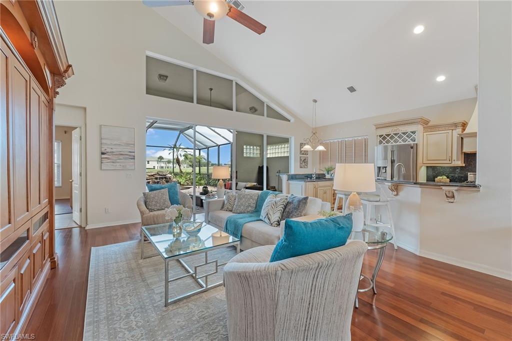 Expansive living area featuring vaulted ceilings with high transom windows, wood-finish flooring, and separate entertainment center