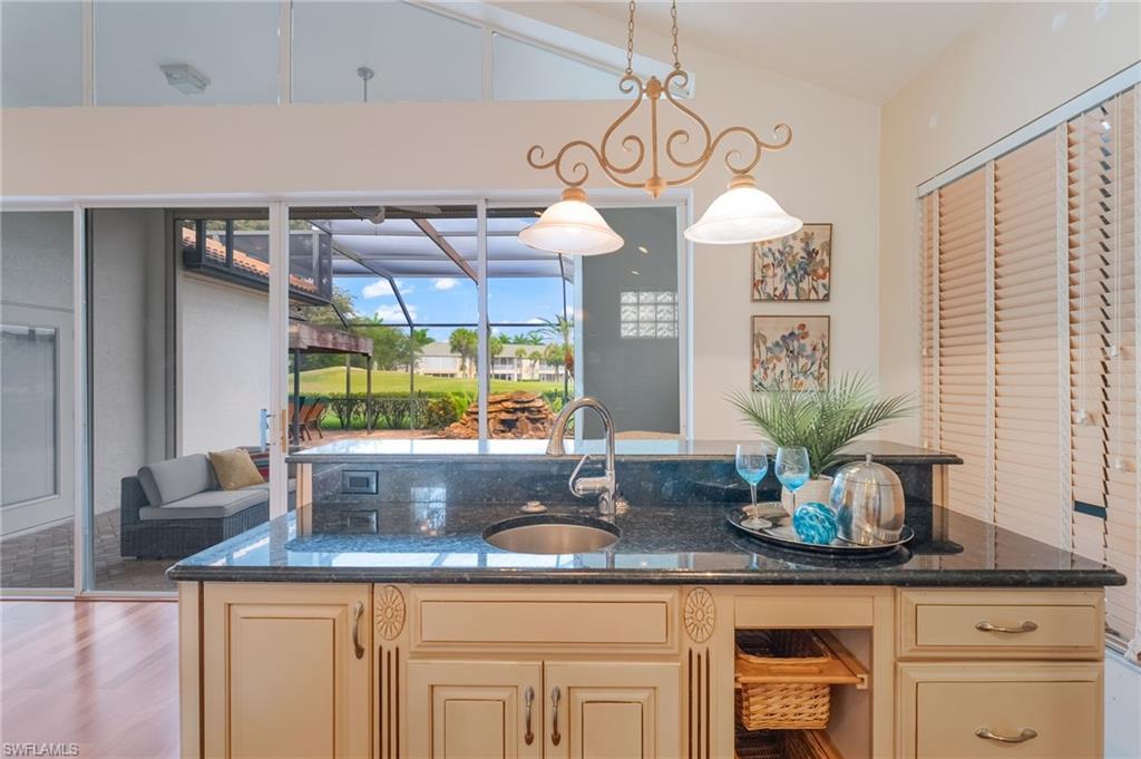Kitchen island featuring a granite, cream-colored cabinetry, built-in icemaker and storage