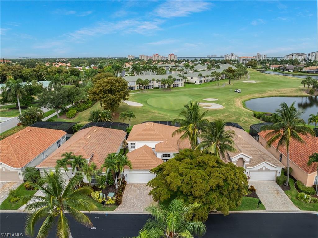 Aerial perspective showcasing a property featuring a paver driveway, manicured landscaping, and a tile roof