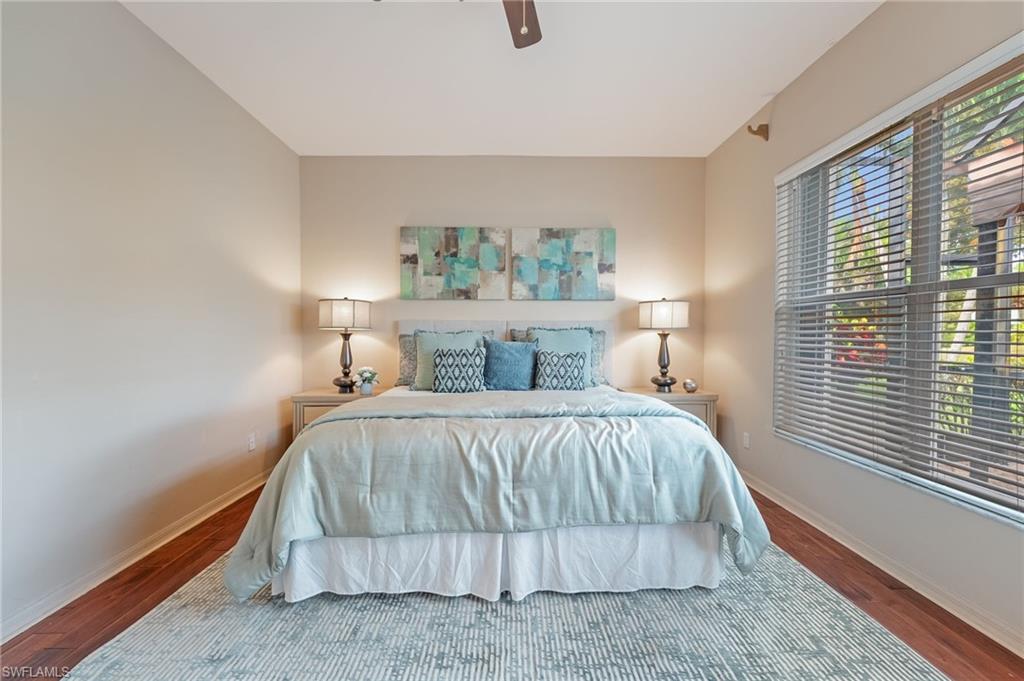 Spacious room featuring wood-finish flooring, a large window with horizontal blinds, and neutral wall tones