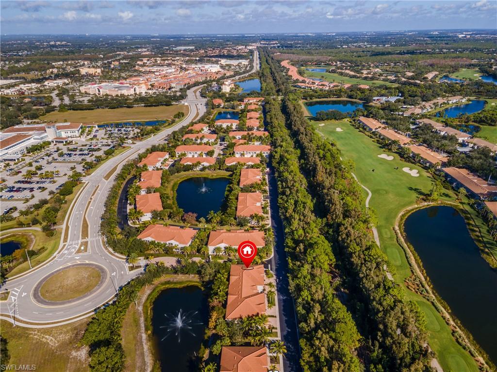 Aerial view of property's location featuring a large body of water, a golf course, and nearby suburban area