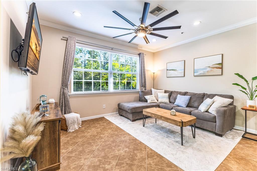 Living area with ornamental molding, a ceiling fan, light tile patterned flooring, and recessed lighting