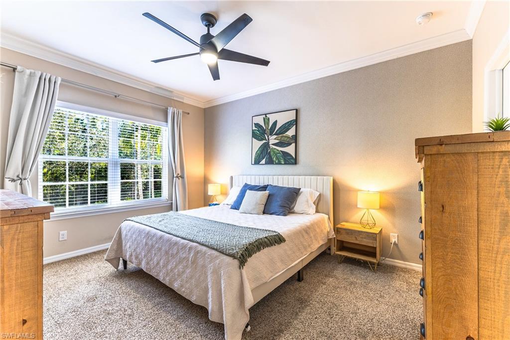 Carpeted bedroom with ornamental molding and a ceiling fan