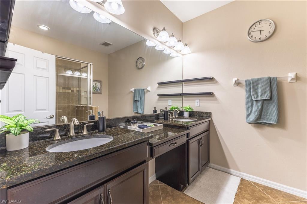 Full bath featuring double vanity, light tile patterned flooring, and a shower stall
