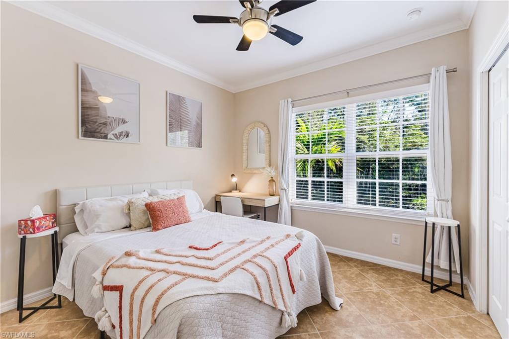 Bedroom with ornamental molding, a closet, a ceiling fan, and light tile patterned floors