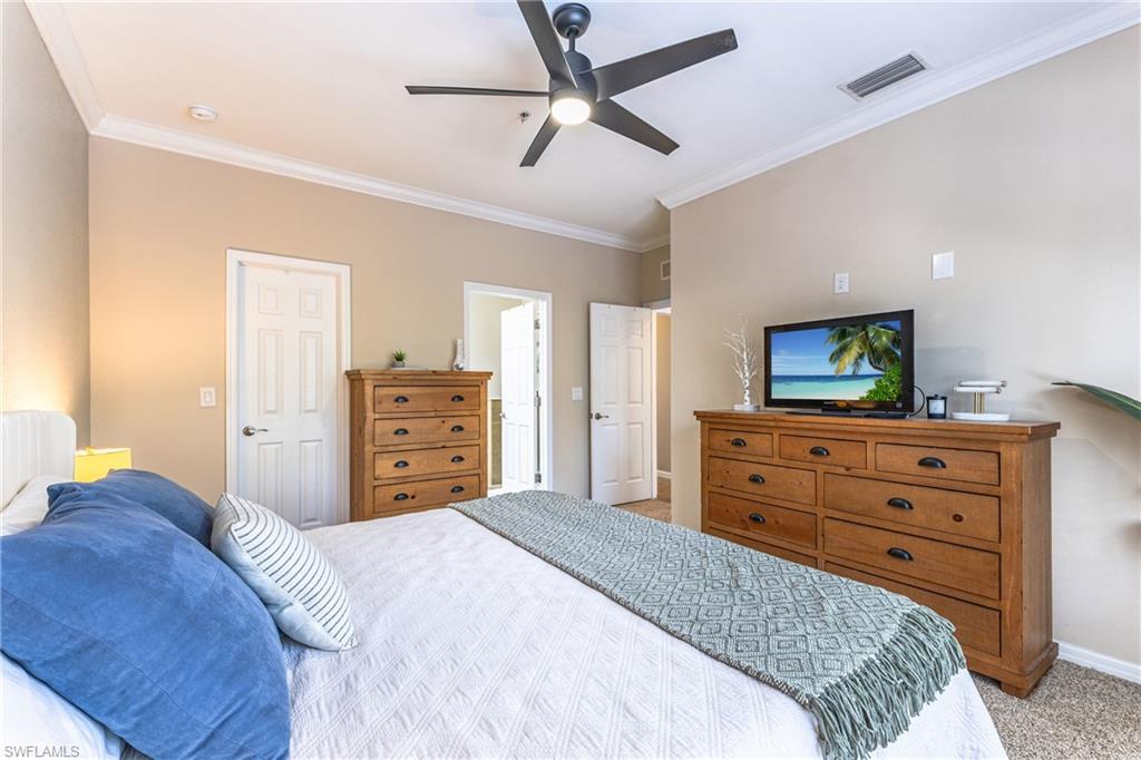 Bedroom with light carpet, crown molding, ceiling fan, and a closet