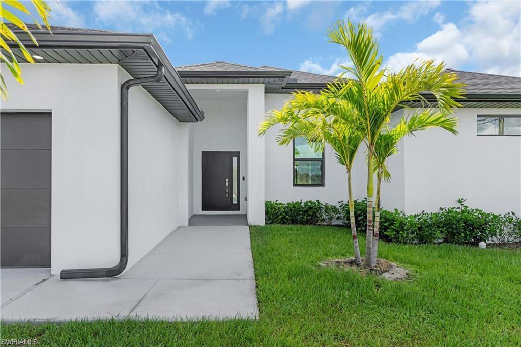 View of exterior entry featuring a garage, stucco siding, and a yard