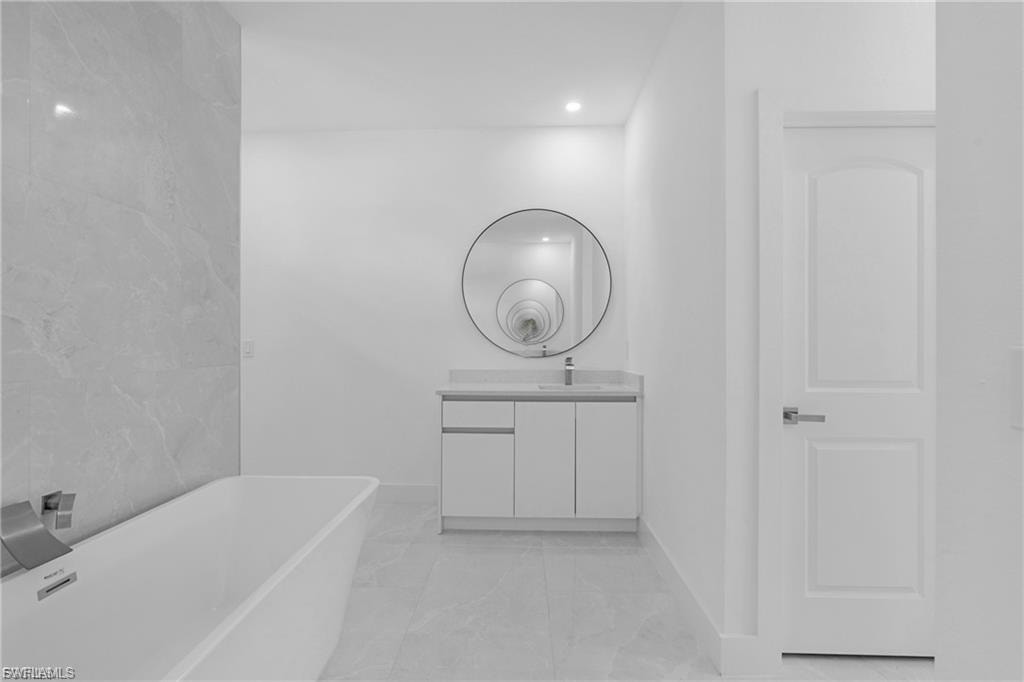 Bathroom featuring a freestanding tub, vanity, and recessed lighting
