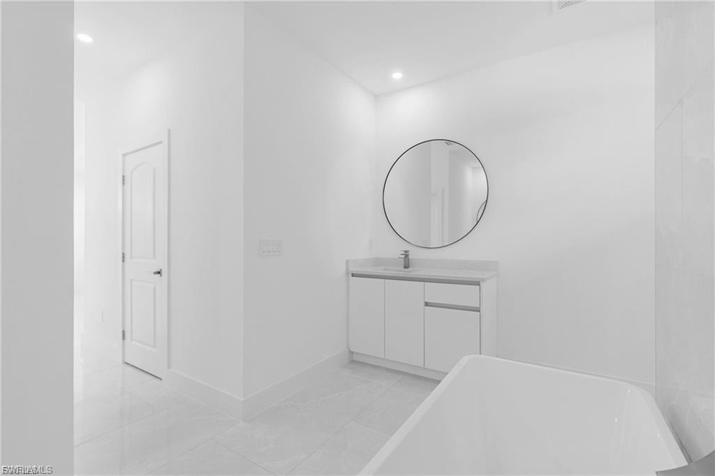 Full bathroom with vanity, a freestanding bath, and recessed lighting