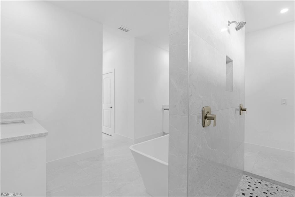 Full bathroom with vanity, a marble finish shower, and a soaking tub