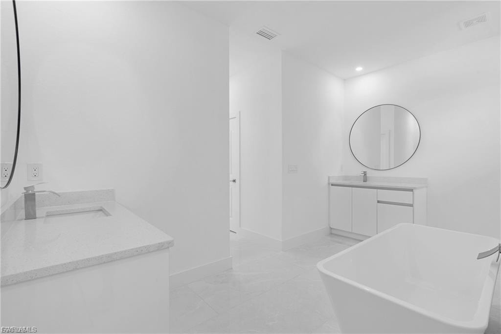 Bathroom featuring two vanities, a freestanding bath, and recessed lighting