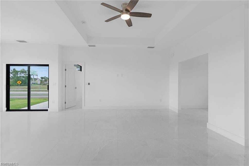 Empty room featuring a raised ceiling and ceiling fan