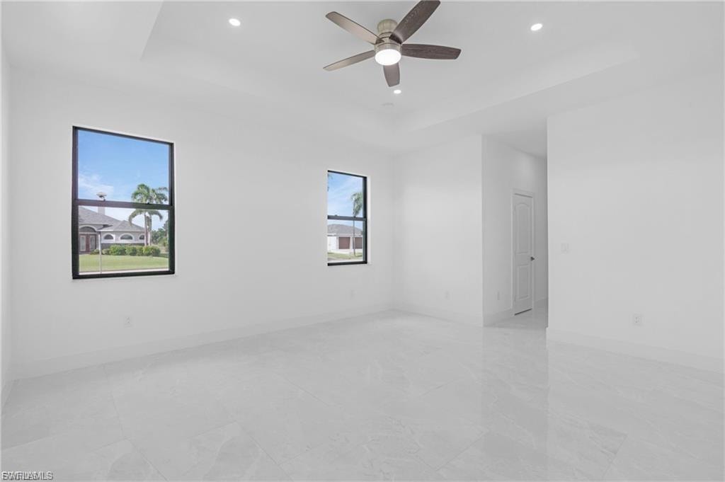Unfurnished room featuring a tray ceiling, recessed lighting, and ceiling fan