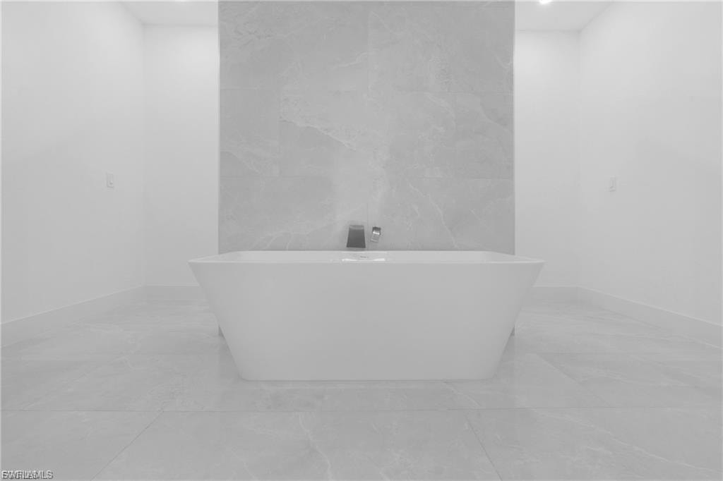Full bath featuring a freestanding bath and tile walls