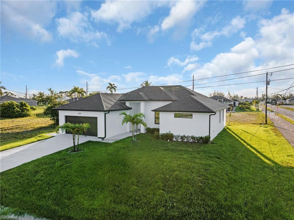 View of front of property with a front lawn, a garage, driveway, and stucco siding