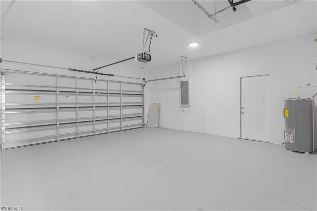 Garage featuring water heater, electric panel, and a garage door opener