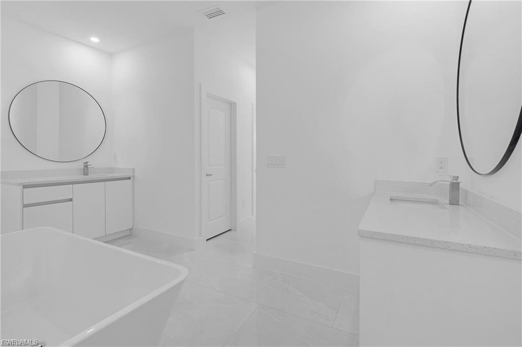 Full bath with vanity, a freestanding bath, and recessed lighting