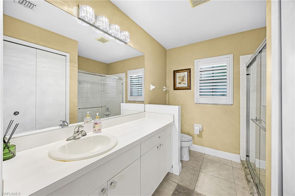 Full bathroom featuring vanity, light tile patterned floors, a stall shower, and healthy amount of natural light