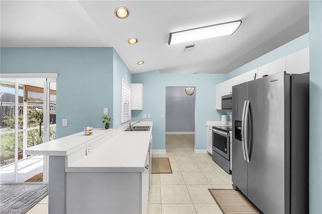 Kitchen with stainless steel appliances, light countertops, a peninsula, white cabinetry, and recessed lighting