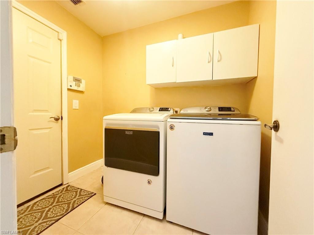 Laundry room with cabinet space, light tile patterned flooring, and washer and dryer