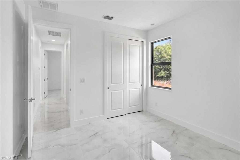 Unfurnished bedroom featuring light marble finish flooring and a closet