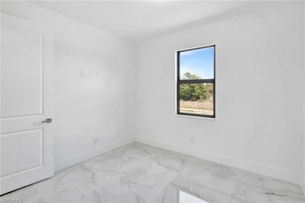 Spare room featuring baseboards and light marble finish floors
