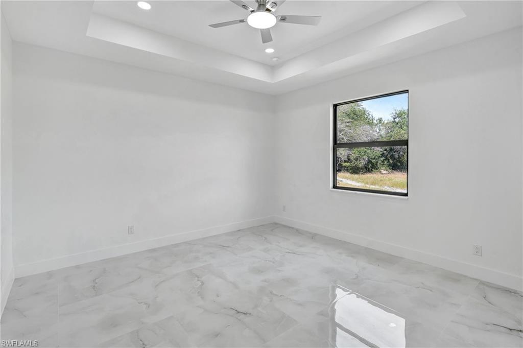Spare room featuring a raised ceiling, recessed lighting, and a ceiling fan