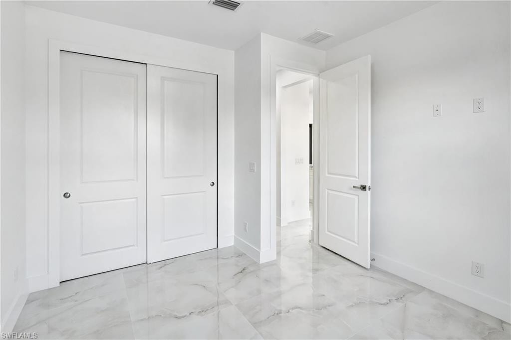 Unfurnished bedroom with a closet and light marble finish flooring