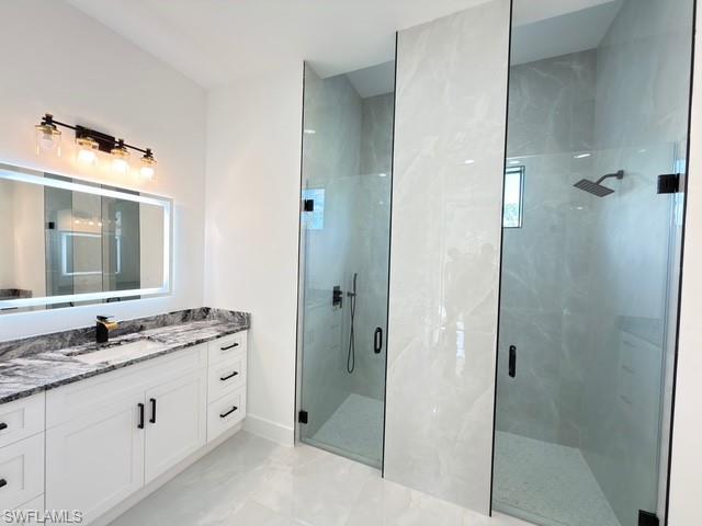 Bathroom featuring vanity and a marble finish shower